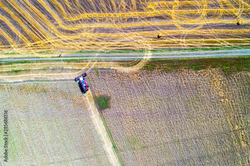Harvester machine working in field . Combine harvester agriculture machine harvesting golden ripe wheat field.. Aerial view.