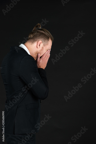 Business and failure concept. Desperate and business man in black suit on isolated black background. Crying smart and middle-aged man with failure