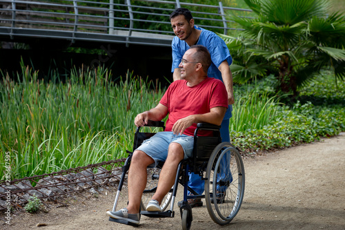 disabled man in a wheelchair talking with his caretaker photo