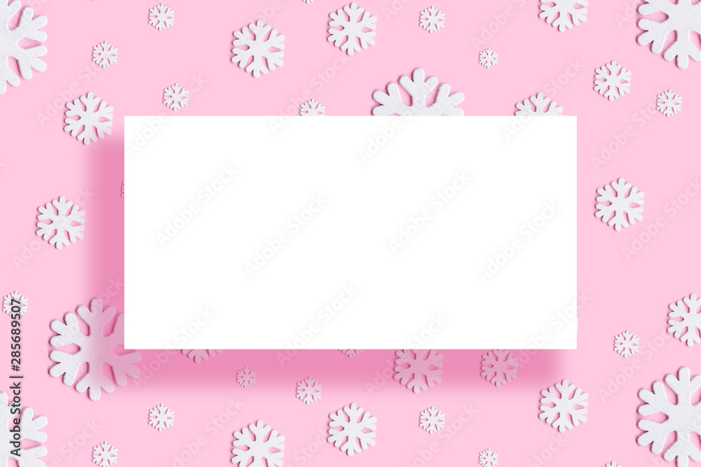 Christmas round frame made of white decor holiday snowflakes on pink background. Flat lay, top view