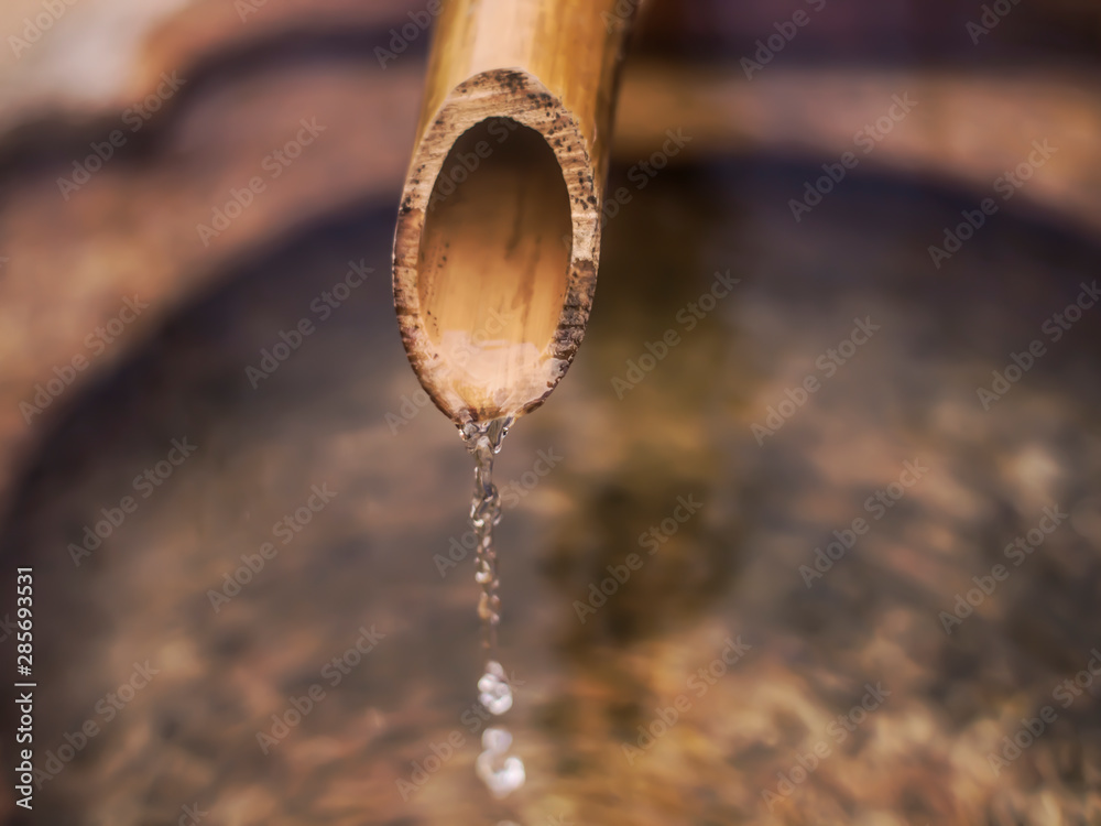 Asian bamboo faucet dropping water in fountain highspeed shot Asian bamboo faucet dropping water in fountain highspeed shot