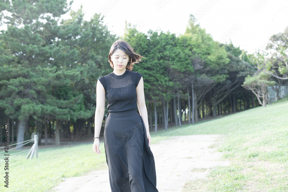 Fototapeta premium 海沿いの公園を歩く若い女性