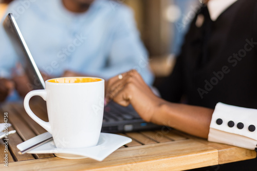Black  African American coworkers doing digital teamwork arround a coffee cup