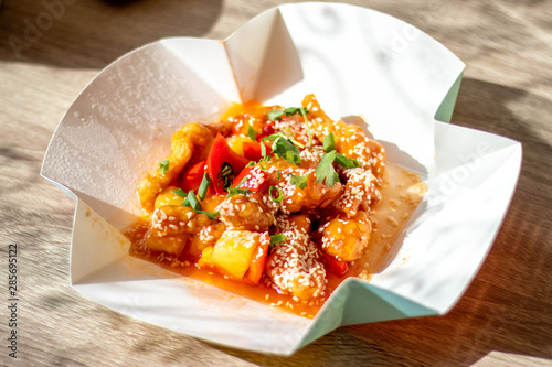 Chinese spicy chicken with food delivery in sweet and sour sauce with pineapple and bell pepper sprinkled with onions