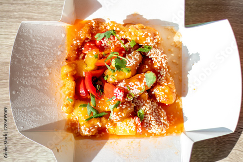 Chinese spicy chicken with food delivery in sweet and sour sauce with pineapple and bell pepper sprinkled with onions