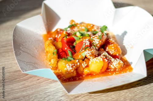 Chinese spicy chicken with food delivery in sweet and sour sauce with pineapple and bell pepper sprinkled with onions