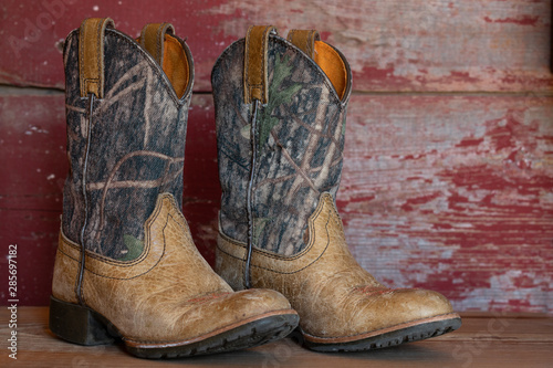 camouflage cowboy boots with red barn board background