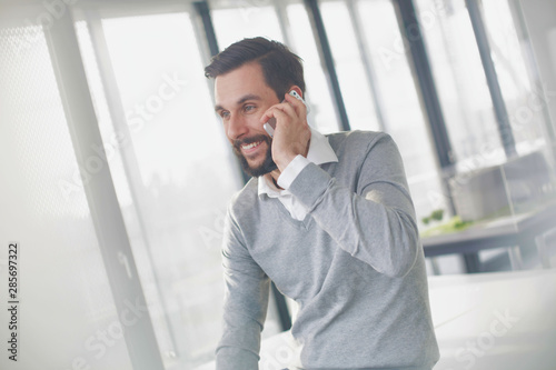 Businessman talking on smartohone while smiling in office