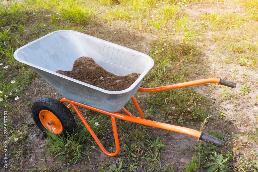 Toned garden wheelbarrow with ground in the backyard on summer day. Gardening concept