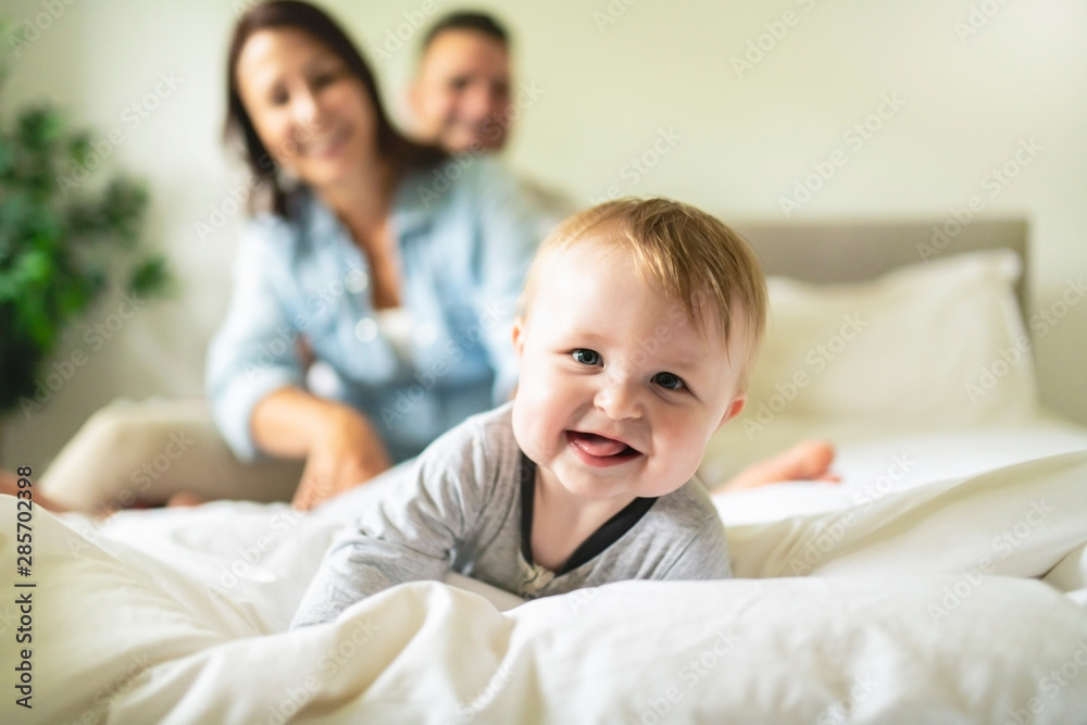 happy family mother, father and son at home in bed