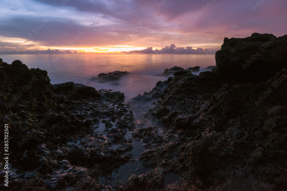 Landscape on a beach at sunset where you can see clouds, silky water and rocks in the foreground. dramatic landscape concept