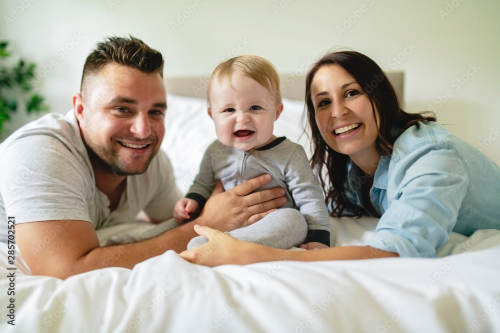 happy family mother, father and son at home in bed