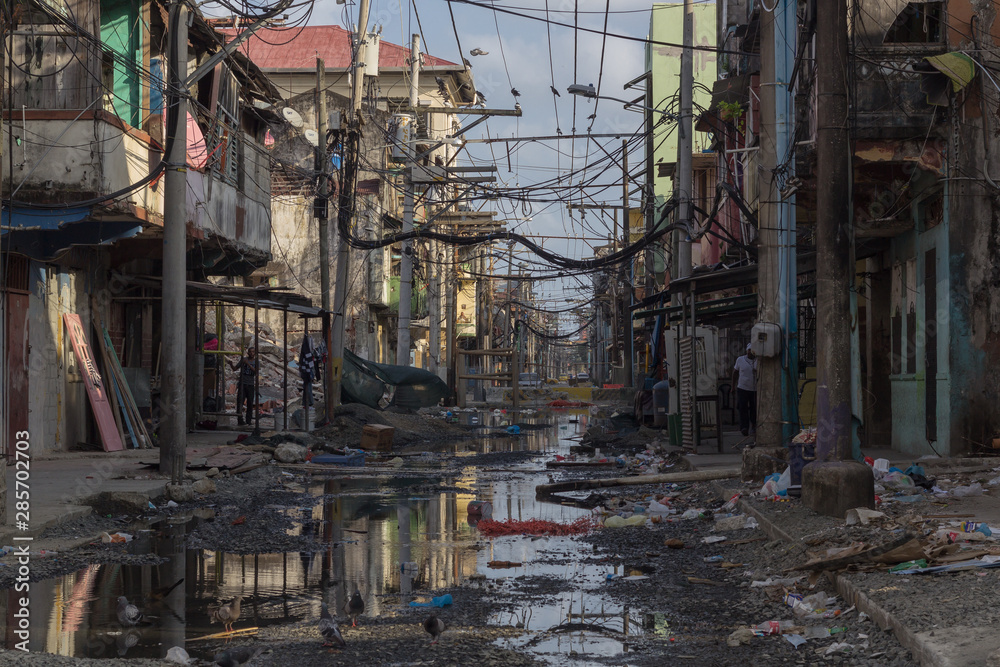 Photograph of an alley where there is stagnant water, garbage and precarious conditions for life. Poverty and inequality concept