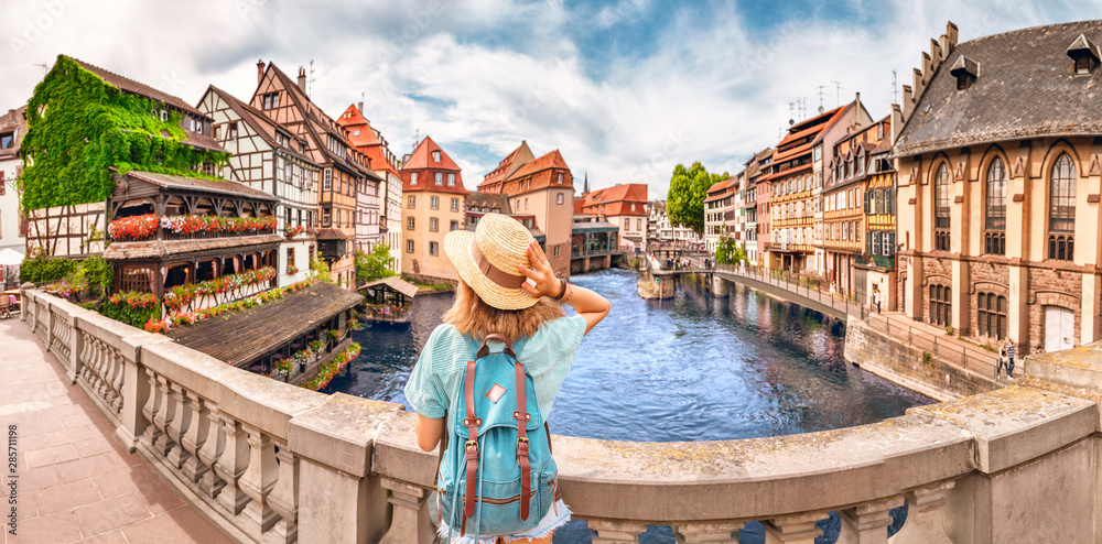 Young girl with backpack standing on a bridge over d Ill river in Strasbourg, France - obrazy, fototapety, plakaty 