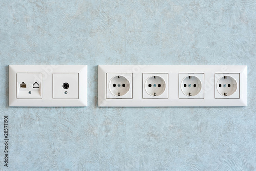 Installation of modern power, communication LAN RJ45 and television sockets on a wall close-up.