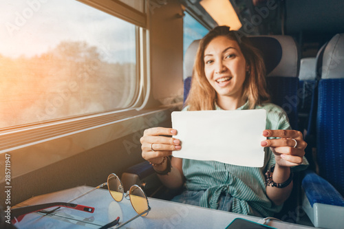 Young asian woman traveling by train and showing her ticket to conductor