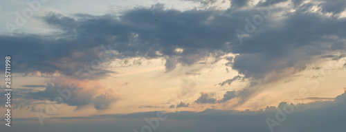 Panorama of the cloudy sky illuminated by the rays of the setting sun