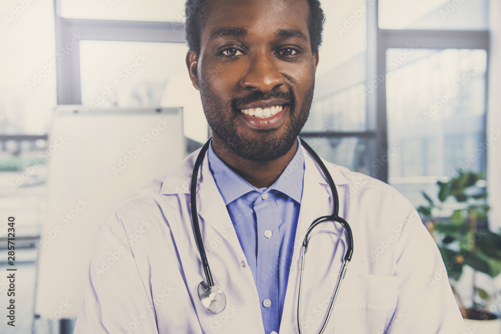 Portrait of an handsome smiling doctor with stethoscope posing with arms crossed in the office Portrait of an handsome smiling doctor with stethoscope posing with arms crossed in the office