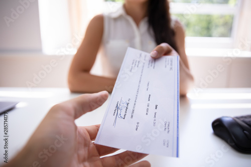 Businesswoman Giving Cheque To Colleague photo