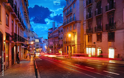 Porto, Portugal. Nighttime city life. Old town street with evening illumination and sky with clouds blue hour. Car speed lights on the road with asphalt. © Yasonya