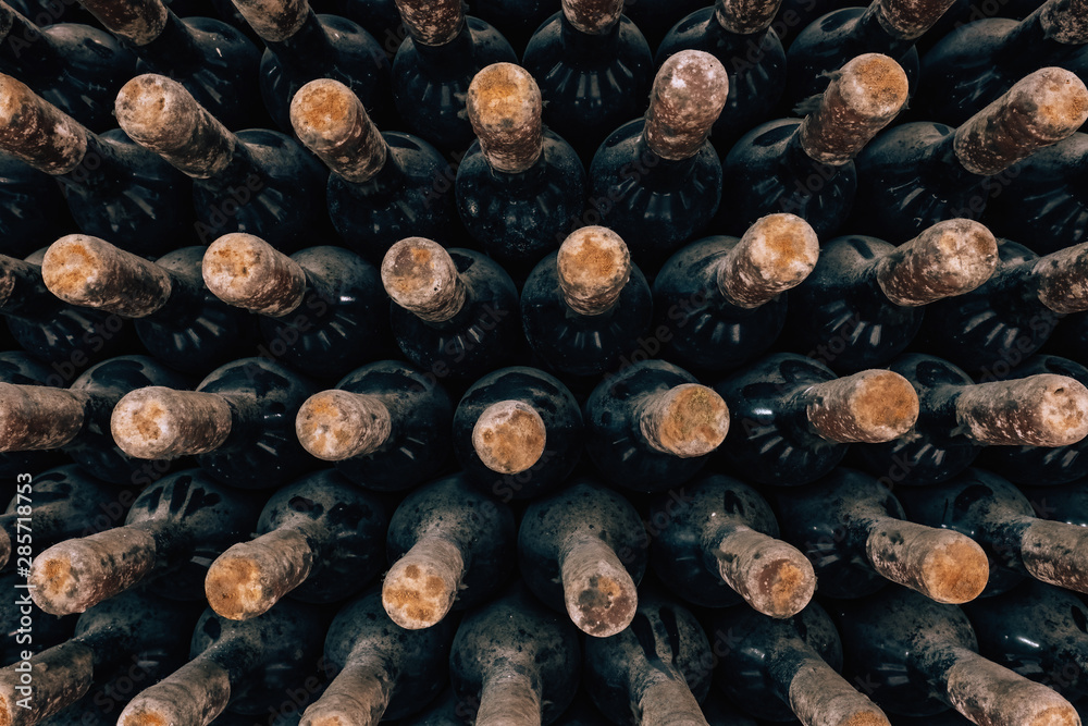 Wine bottles stacked up in old wine cellar close-up background Wine bottles stacked up in old wine cellar close-up background
