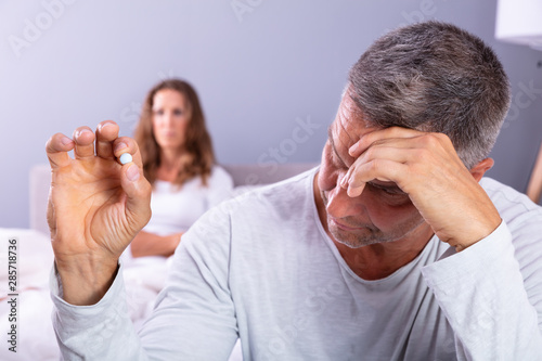 Schilderij op canvas Man Suffering From Erectile Dysfunction Holding Pill In Hand