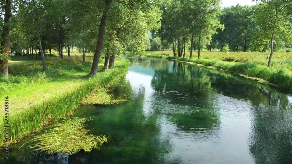 Beautiful Gacka river flowing between trees and fields, summer view, Lika region of Croatia Beautiful Gacka river flowing between trees and fields, summer view, Lika region of Croatia