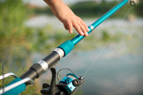 Close-up of a child's hand holding a fishing rod. Spin fishing reel