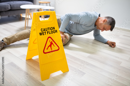 Canvastavla Man Falling On Wet Floor In Front Of Caution Sign