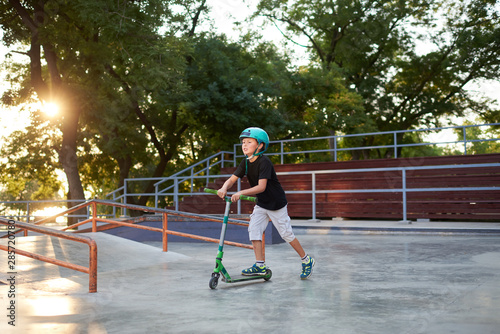 A boy on a scooter and in protective helmet do incredible stunts in skate park. Extreme jump. The concept of a healthy lifestyle and sports leisure © oes