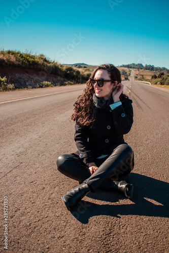 Modelo sentanda no meio de uma estrada deserta
