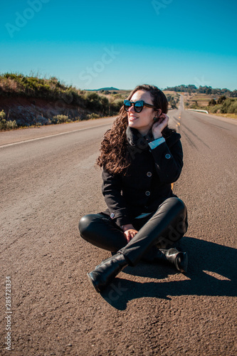Modelo sentanda no meio de uma estrada deserta © Adriano
