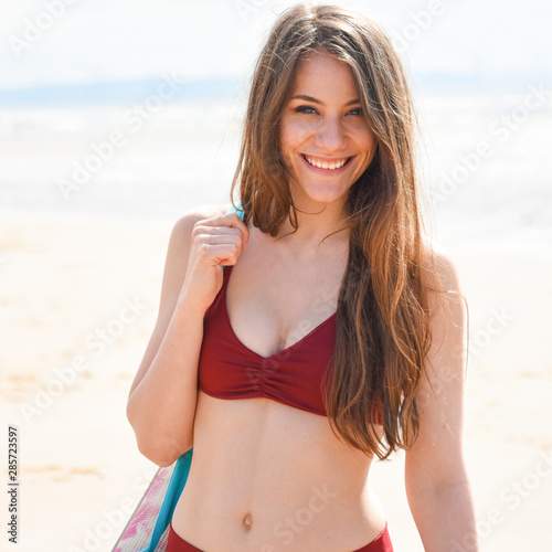 pretty young woman on the beach with a yoga mat