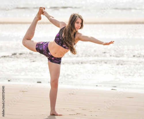 Yoga on the beach with a beautiful young woman in a bikini