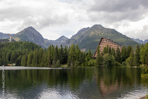 Mountain lake with hotel in the background under high mountains in the clouds. Strbske Pleso, High Tatras, Slovakia.