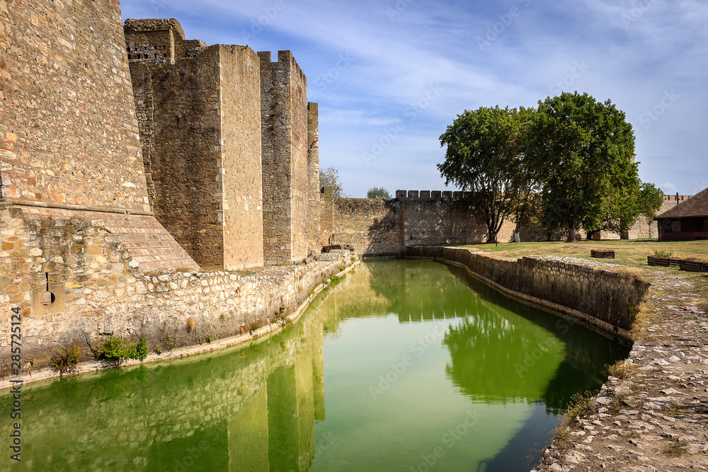 Channel with green, reflective water surrounding ancient Smederevo fortress