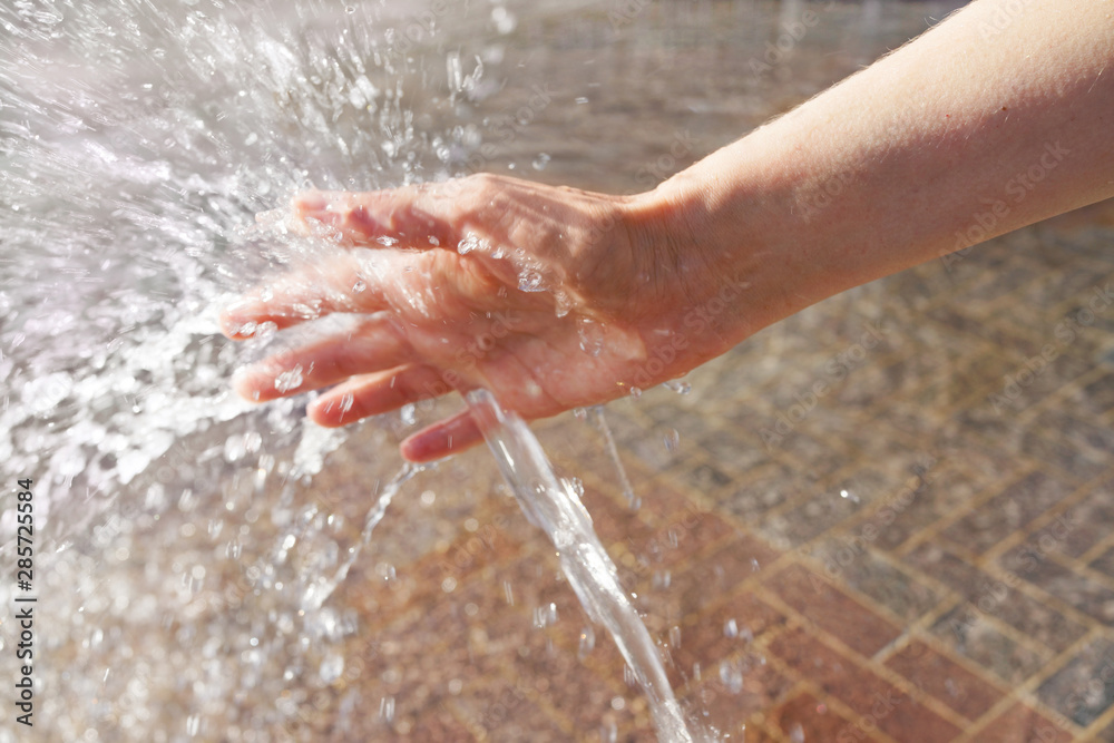 Fototapeta premium woman's hand cooling in a water fountain