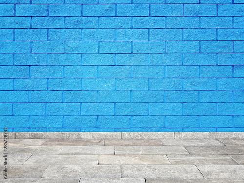 Brick wall with regular shapes and a rough surface. Empty blue background facade building with sidewalk
