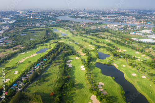 Aerial panoramic view of golf course and houses in city.