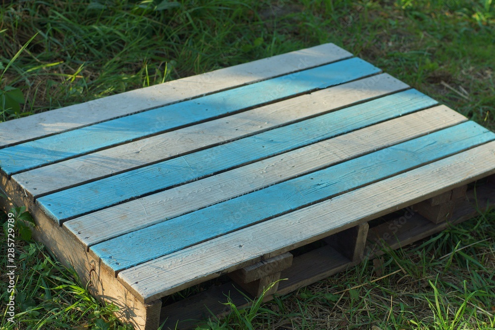 striped colored wooden table from the pallet lies on the green grass in the park striped colored wooden table from the pallet lies on the green grass in the park