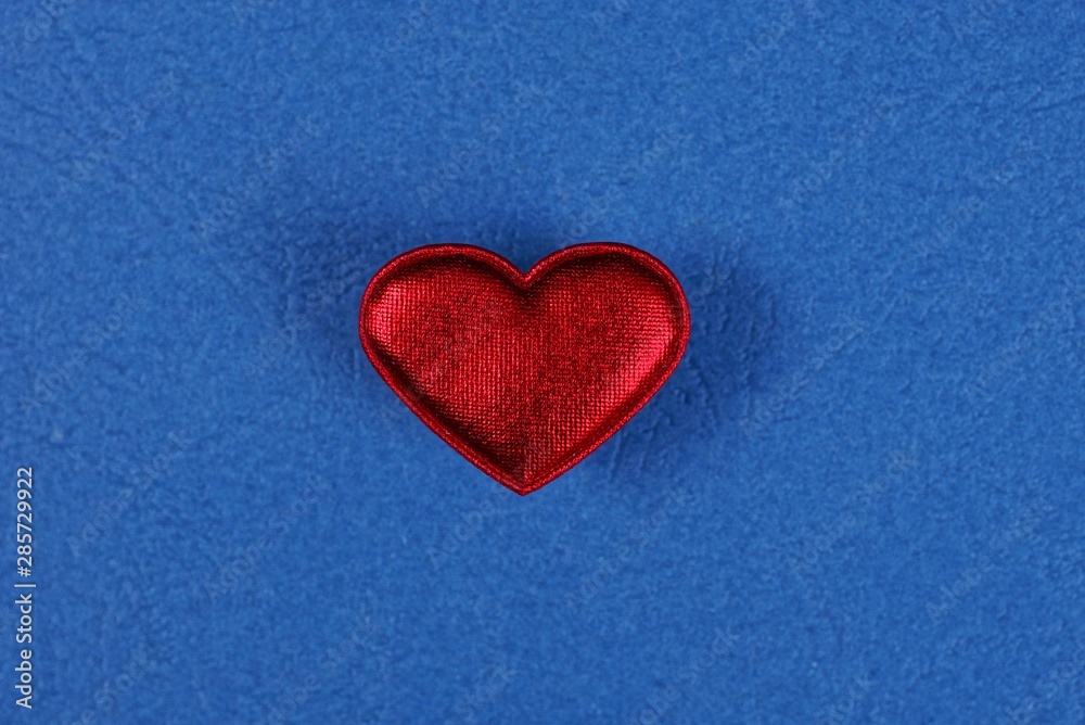 one little red heart made of matter lies on a blue table one little red heart made of matter lies on a blue table