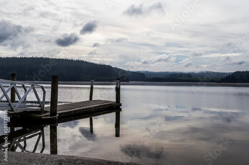 Lake Maraetai in Mangakino, Waikato district, New Zealand. Still waters, small boat jetty, reflections of cloud and sky. Moody, peaceful, reflective. Hydroelectric station, recreational activities. photo