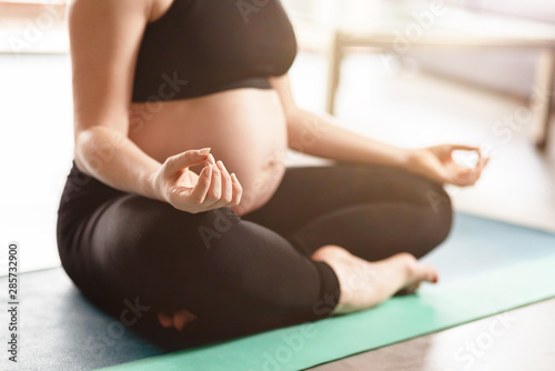 Trying to calm down. Young pregnant woman doing yoga. Copy space in upper right part