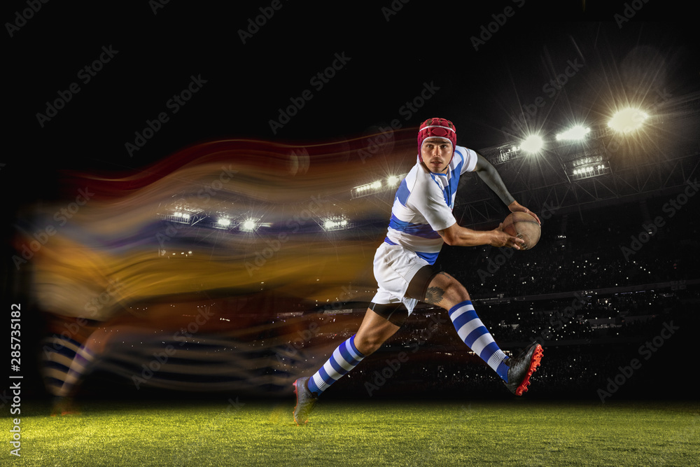 New star of the competitive. One caucasian man playing rugby on the stadium in mixed light. Fit young male player in motion or action during sport game. Concept of movement, sport, healthy lifestyle.