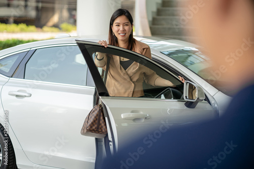 Backside of Receptionist welcoming the asian customer woman to visit maintainance service center for checking the car in showroom
