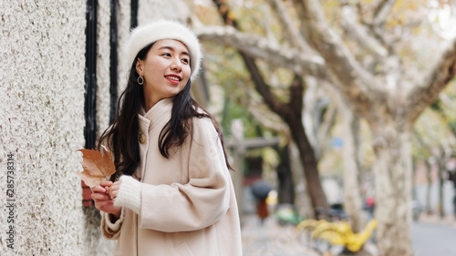 Beautiful young brunette woman in white beret and woolen sweater posing with blur street background. Outdoor fashion portrait of glamour young Chinese cheerful stylish lady, street photography.