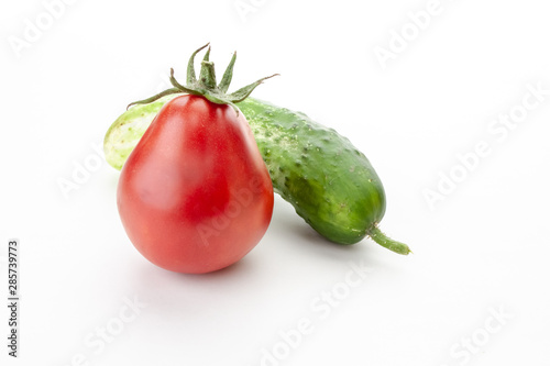 green cucumber and red tomato just from the garden on a white background