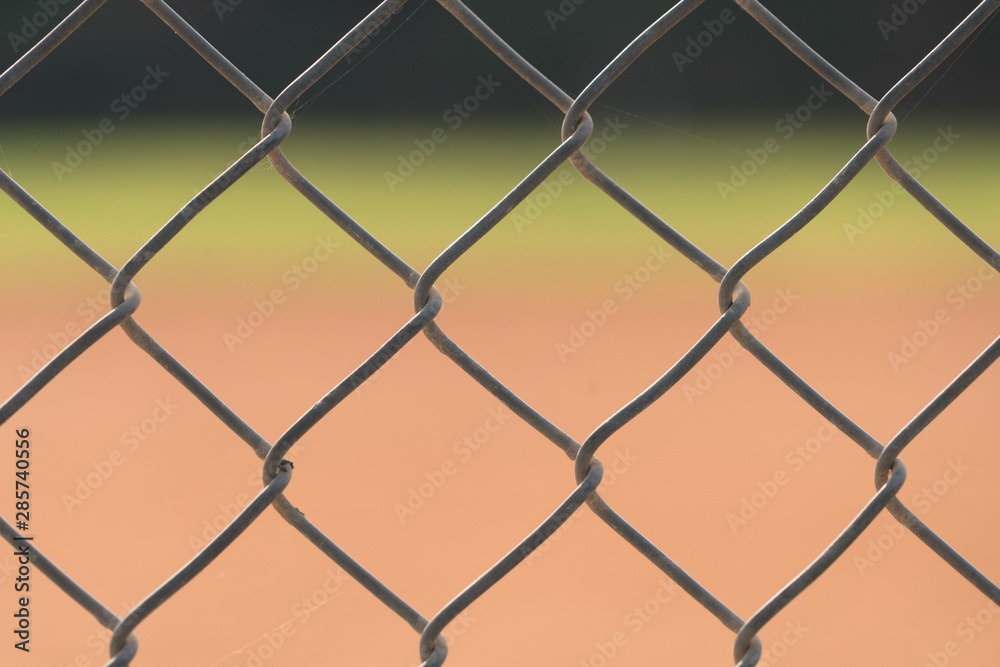 Fototapeta premium Close up picture of chain link fence with blurred baseball field in background.