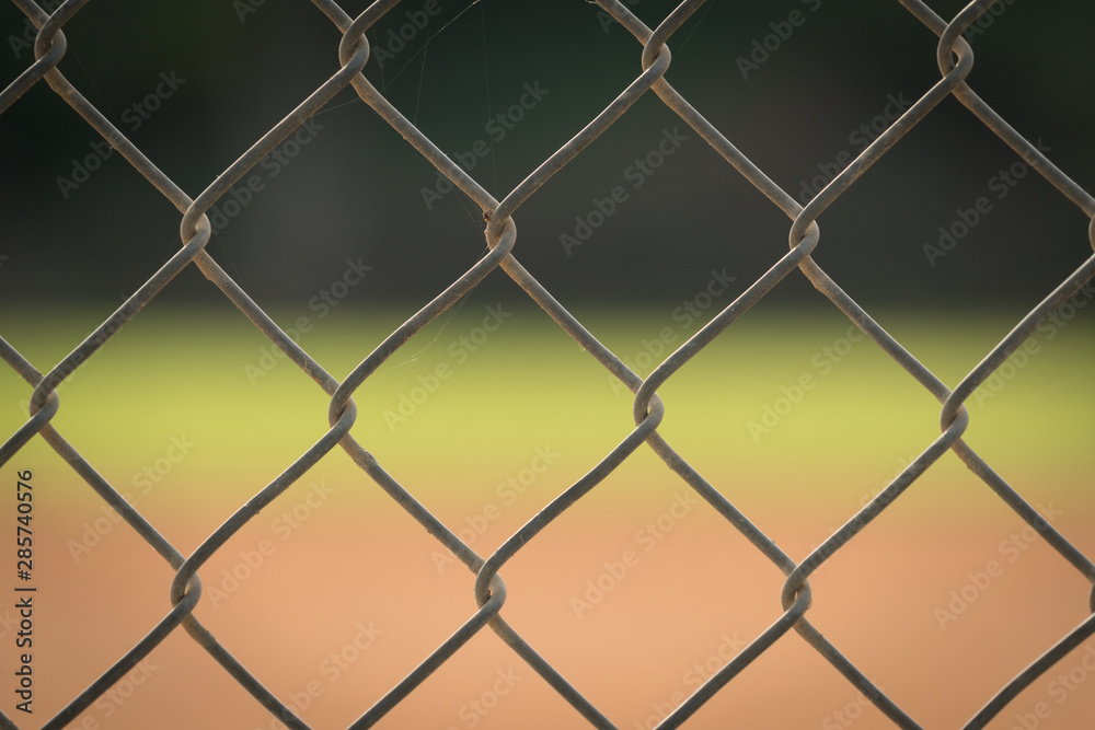 Close up picture of chain link fence with blurred baseball field in background. Close up picture of chain link fence with blurred baseball field in background.