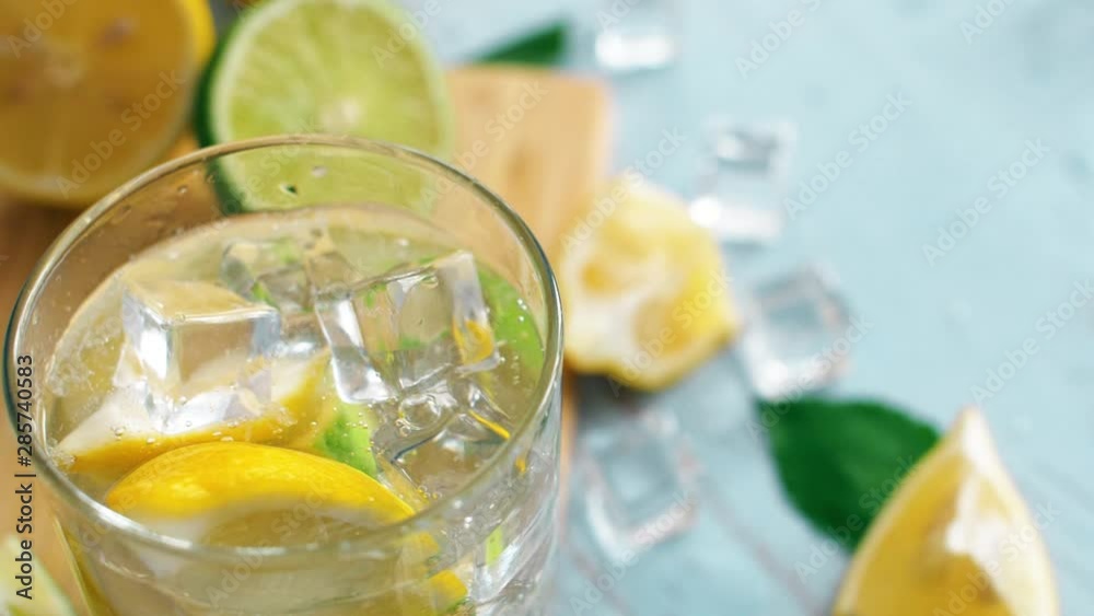 Close up slow motion of ice falling intro glass with slice lime and lemon. Fresh coctail stay on chopping board. Summer drink. Close up slow motion of ice falling intro glass with slice lime and lemon. Fresh coctail stay on chopping board. Summer drink.